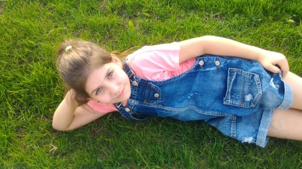 The girl lies on the grass and smiles