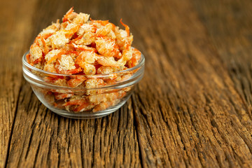 Dried shrimp in glasses cup on wood table perspective