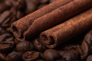 Two sticks of cloves against the background of coffee beans, close-up