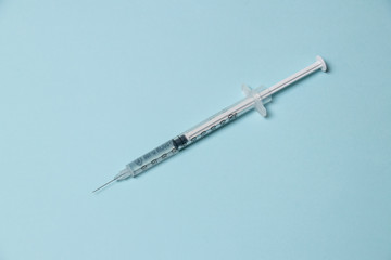 Parts of a medical syringe isolated on a blue background. Needle, barrel of syringe with plunger,...