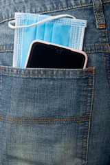 Facial mask and mobile phone in jeans back pocket; 
