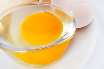 Image of yolk and squirrel in a transparent round cup on a plate. Egg in a transparent cup on a plate. Closeup