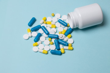 Assorted pharmaceutical medicine pills, tablets and capsules over blue background
