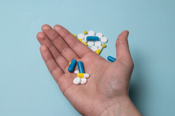 Hand of a man holding a pill. Doctor's hand on a blue background. Viagra medicine concept, medicine for the stomach, erection, sleep, digestive, drugs