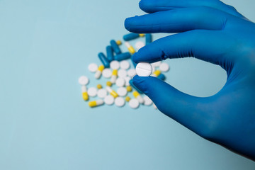 Hand of a man holding a pill. Doctor's hand in blue gloves on a blue background. Viagra medicine concept, medicine for the stomach, erection, sleep, digestive, drugs