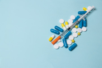 Medical syringe and pills on a dark blue background, health and vaccination concept.