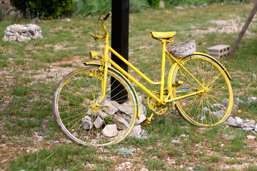 Fototapeta premium Old bike, painted yellow and set as decoration in the Mediterranean village in Dalmatia region, Croatia.