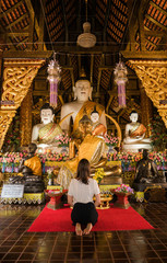 Woman prays inside a buddhist temple in the city of Chiang Mai, Thailand