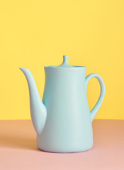 minimalism concept with light pastel colored blue teapot on yellow background.  Flat lay. Tea time concept. Empty space