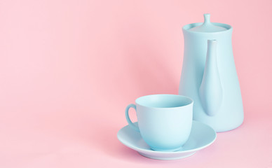 Fototapeta na wymiar minimalism concept with light pastel colored blue cups teapot and plate on pink background.