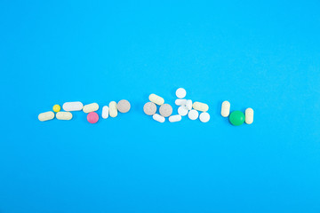 Heap of colorful pills on blue background