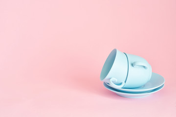 minimalism concept with light pastel colored blue cups and plate on pink background.