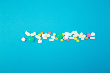 Heap of colorful pills on blue background