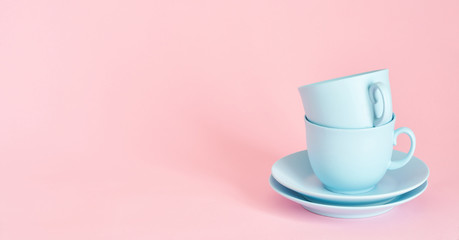 minimalism concept with light pastel colored blue cups and plate on pink background.