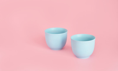 minimalism concept with light pastel colored blue cups on pink background.