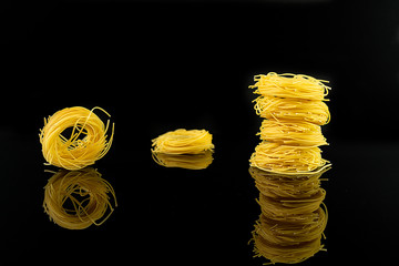 Italian pasta spaghetti sockets isolated reflection on glossy black surface.