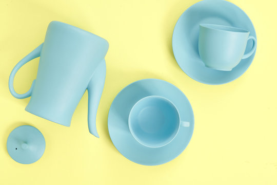 minimalism concept with light pastel colored blue teapot, plates and cups on yellow background.  Flat lay. Tea time concept. Empty space - Powered by Adobe