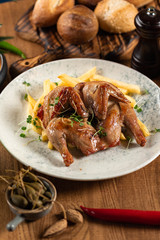 tobacco chicken with french fries, pickled pepper and microgreen on a wooden table. close-up