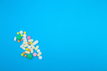 Heap of colorful pills on blue background