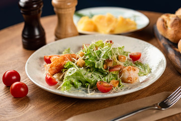 Caesar salad with prawns on a wooden table. 