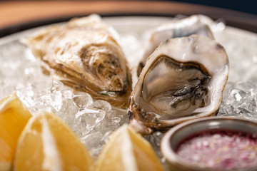 Fresh oysters on ice with lemon and red onion wine sauce. close-up