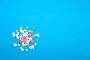 Heap of colorful pills on blue background