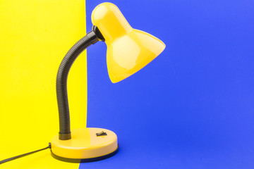 Yellow desk lamp isolated on blue and yellow background