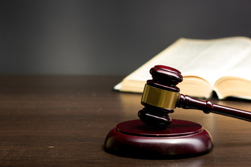 Law concept - Open law book with a wooden judges gavel on table in a courtroom or law enforcement office isolated on white background. Copy space for text