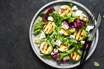 Mix salad with grilled zucchini and sauce on a black background.Top view with copy space.