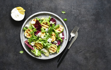 Mix salad with grilled zucchini and sauce on a black background.Top view with copy space.