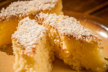 Coconut cake sliced in brown dish on wooden table. Focus seletive.