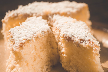 Coconut cake sliced in brown dish on wooden table. Focus seletive.