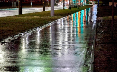 Night city with the reflection of lights on a road