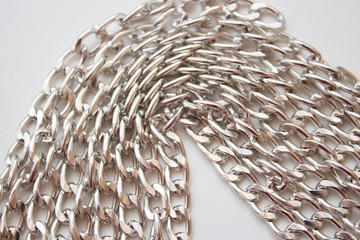  Metal chain closeup as a background, links of a silver chain on a white table, top view