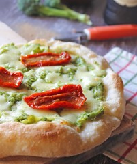 Delicious homemade pizza, very healthy dough garnished with broccoli cream, mozzarella cheese and dried tomatoes.