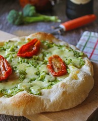 Delicious homemade pizza, very healthy dough garnished with broccoli cream, mozzarella cheese and dried tomatoes.