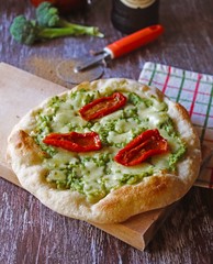 Delicious homemade pizza, very healthy dough garnished with broccoli cream, mozzarella cheese and dried tomatoes.