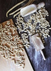 Italian typical pasta and kitchen utensils on wood table. Malloreddus of semolina in the making....