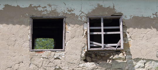  Wall of old blocks with a damaged wooden window without glass. Vintage village building