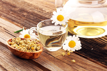 Fototapeta na wymiar chamomile cup of tea with chamomile flowers on wooden rustic table