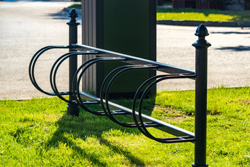 Green empty modern equipment for parking bicycles on street near office building, free space. Metal parking for bikes.