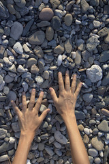 Woman hands touching stones on the beach