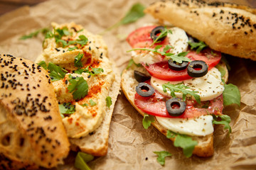 Two delicious sandwiches with hummus, tomato, mozarella cheese, herbs and olives