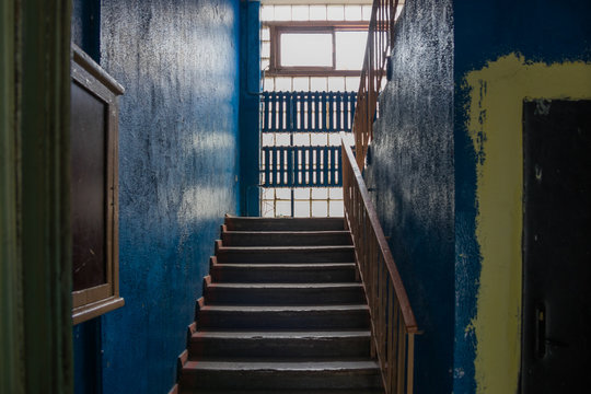 Concrete staircase in an old soviet house. Walls painted with blue paint