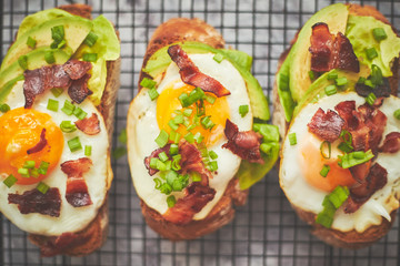 Breakfast concept. Tasty delicious homemade toasts with fried egg, bacon, avocado, lettuce and chive