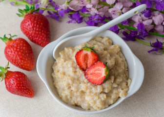 Oatmeal with strawberries in a white plate with a spoon. Lunch. Healthy food. Healthy lifestyle. Close-up