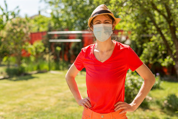 Portrait of a beautiful girl in her backyard on a sunny day wearing a surgical mask because of the coronavirus epidemic. Home life during quarantine or self-isolation