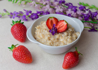 Homemade oatmeal with strawberries in a white plate. Healthy breakfast. Oatmeal with sliced ​​strawberries.