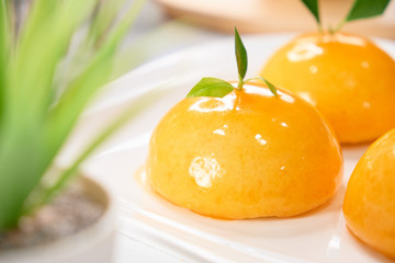 colorful glazing orange dome cake set on cafe table.