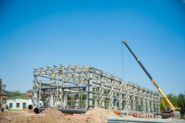 Steel frame workshop is under construction against a blue sky